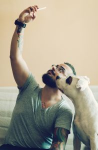 Cheerful man making selfie with his dog, american staffordshire terrier.